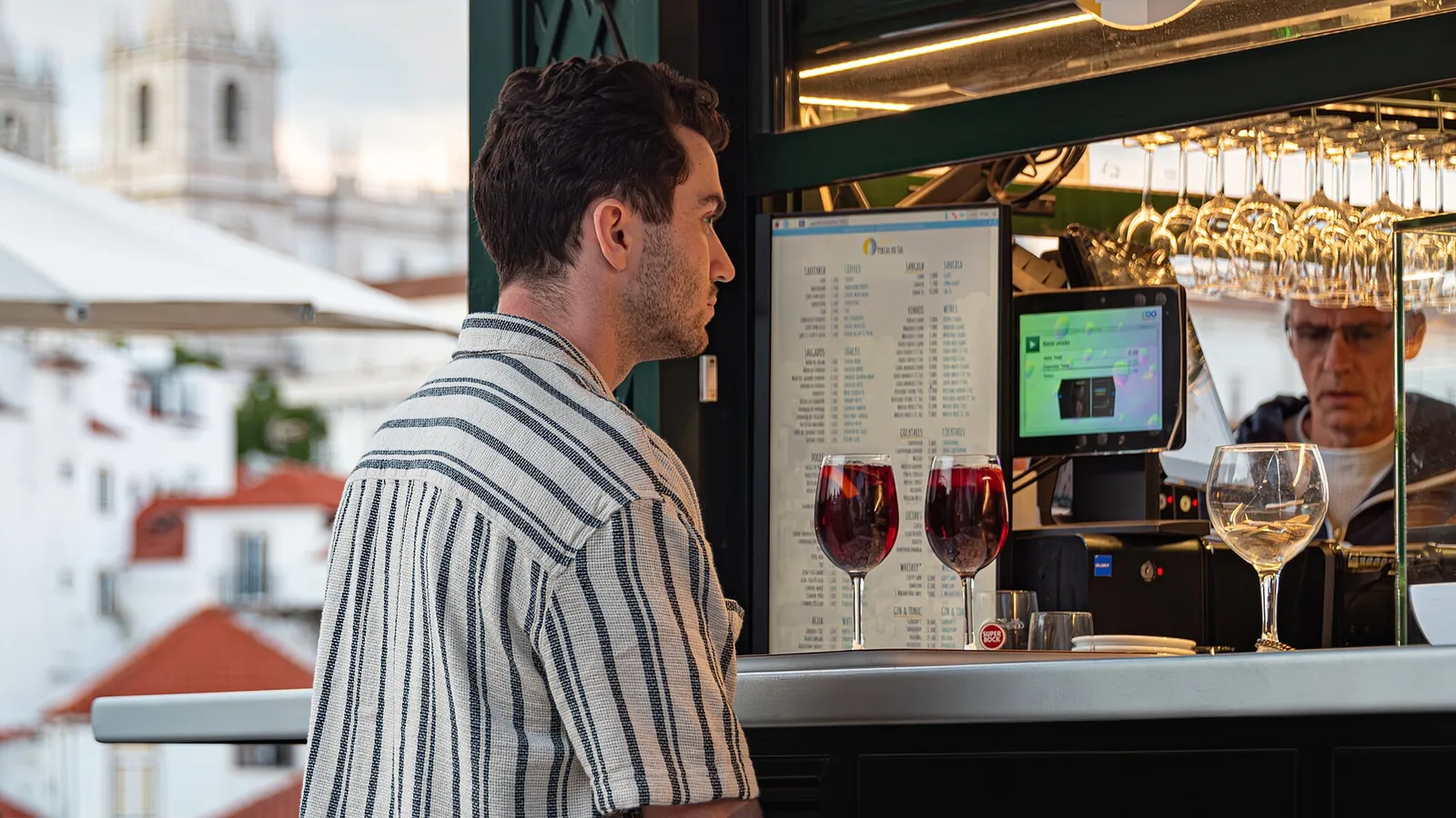 Ordering a glass of wine at the Portas do Sol kiosk, with Alfama's rooftops behind
